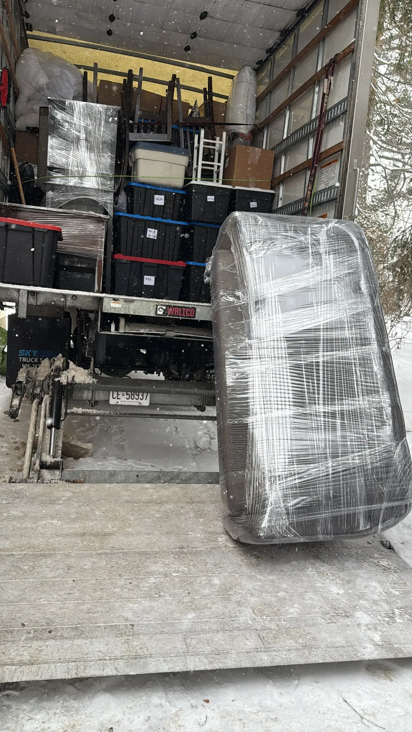 Wrapped commercial item beside a loaded moving truck in winter