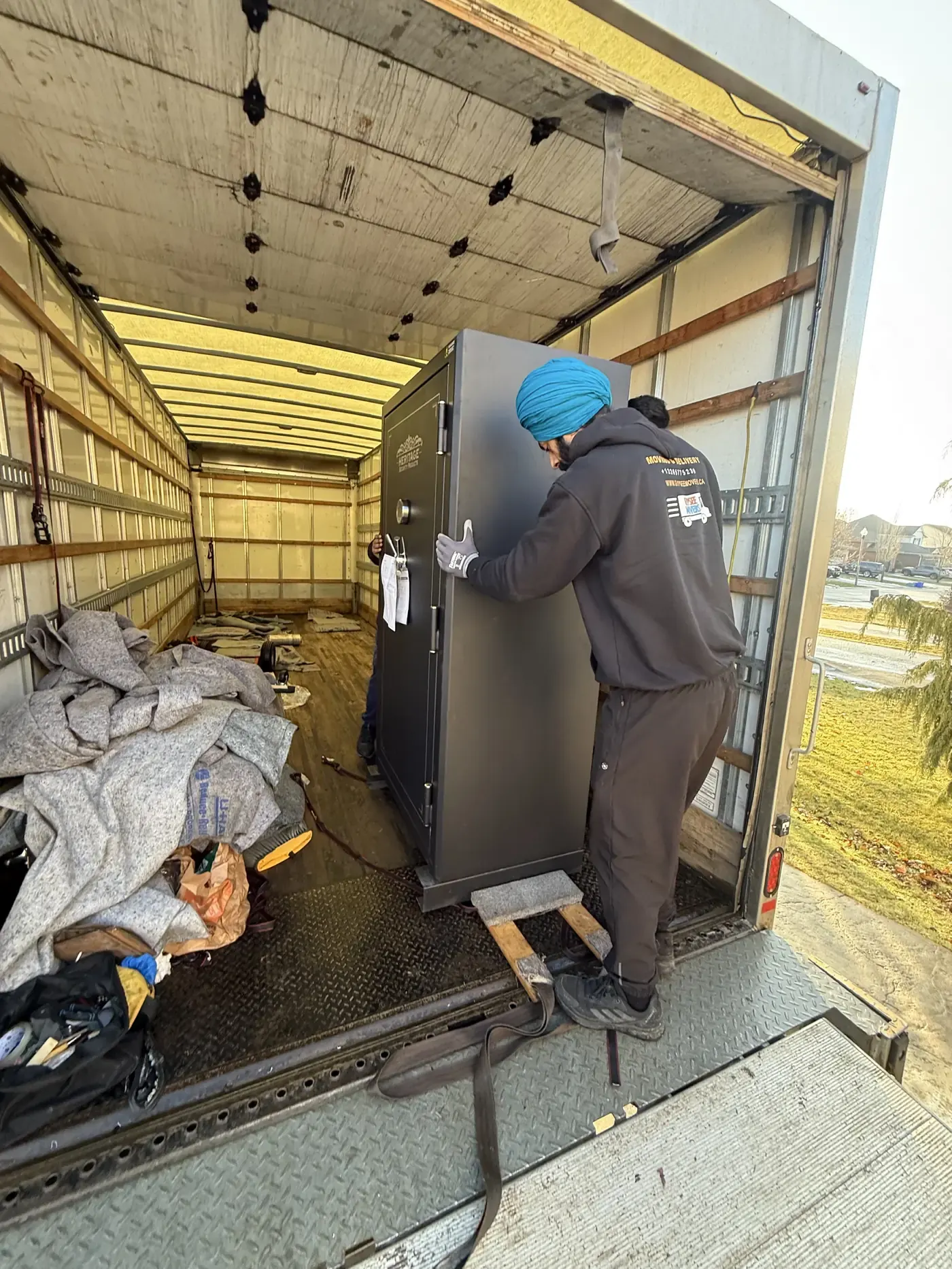 Commercial movers loading a heavy safe into the moving truck