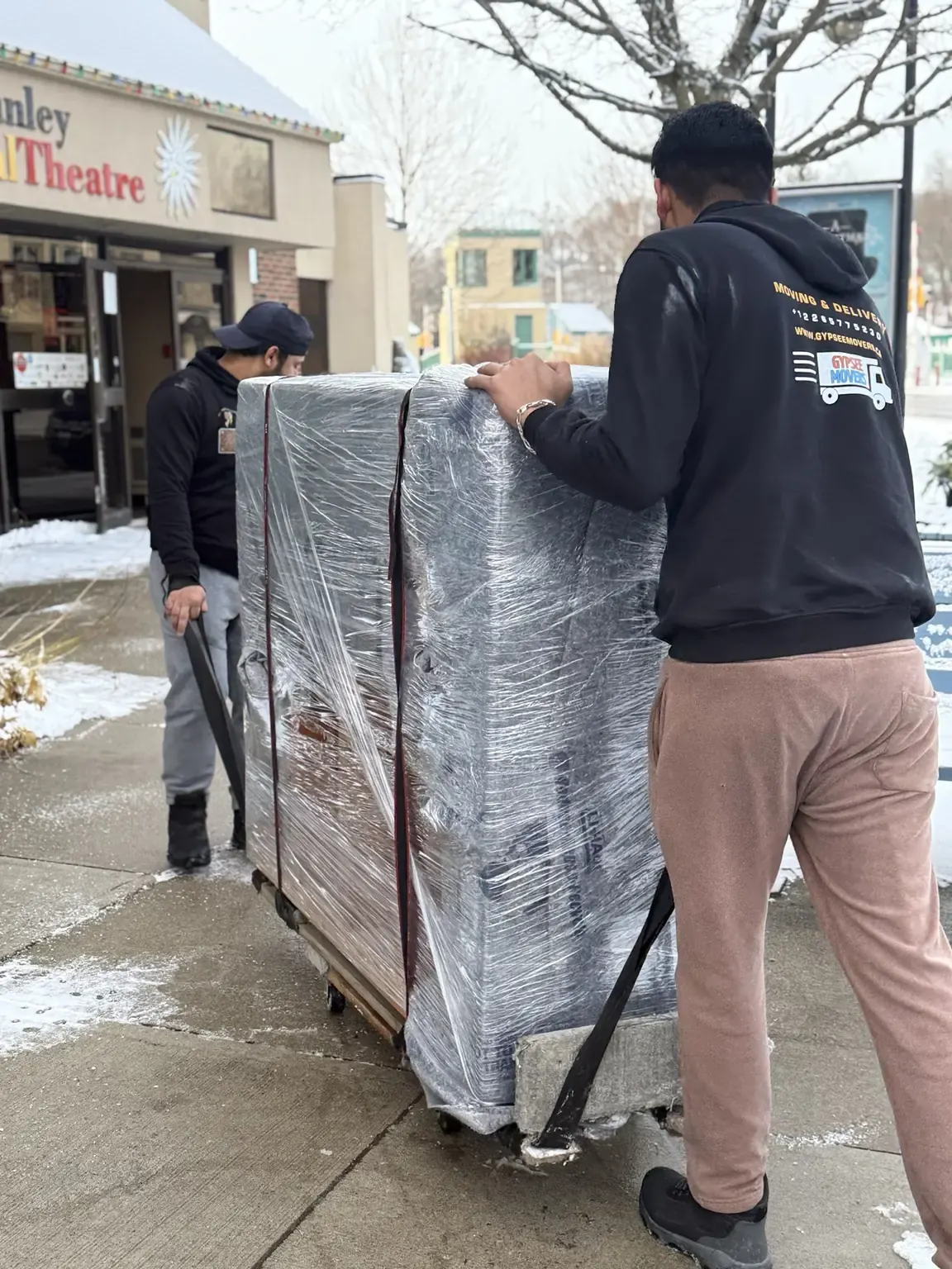 Gypsee Movers moving a large wrapped commercial item outside a business
