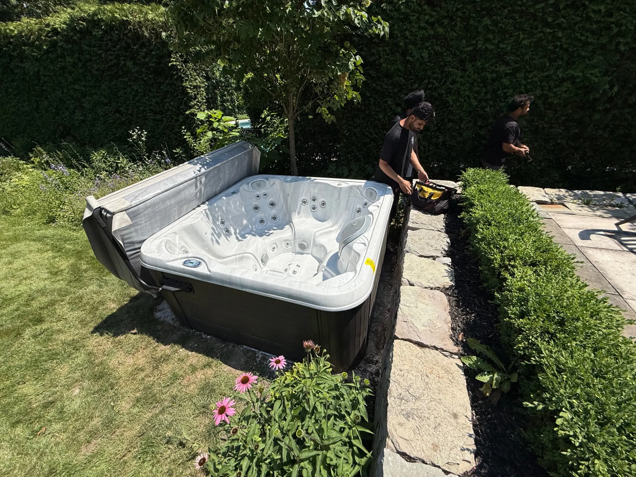 Gypsee Movers removing a hot tub in Stratford Ontario by lifting it over a stone retaining wall because there was no side yard access.