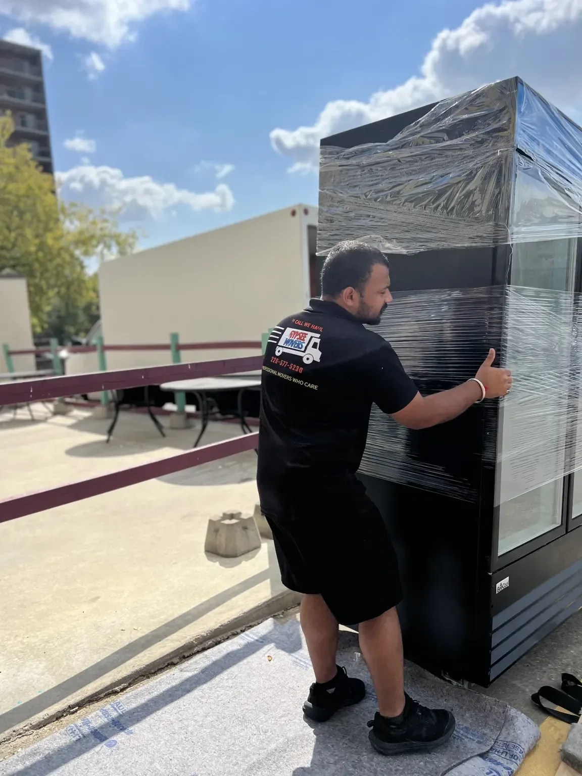 Gypsee Movers moving wrapped furniture on a balcony during a local move