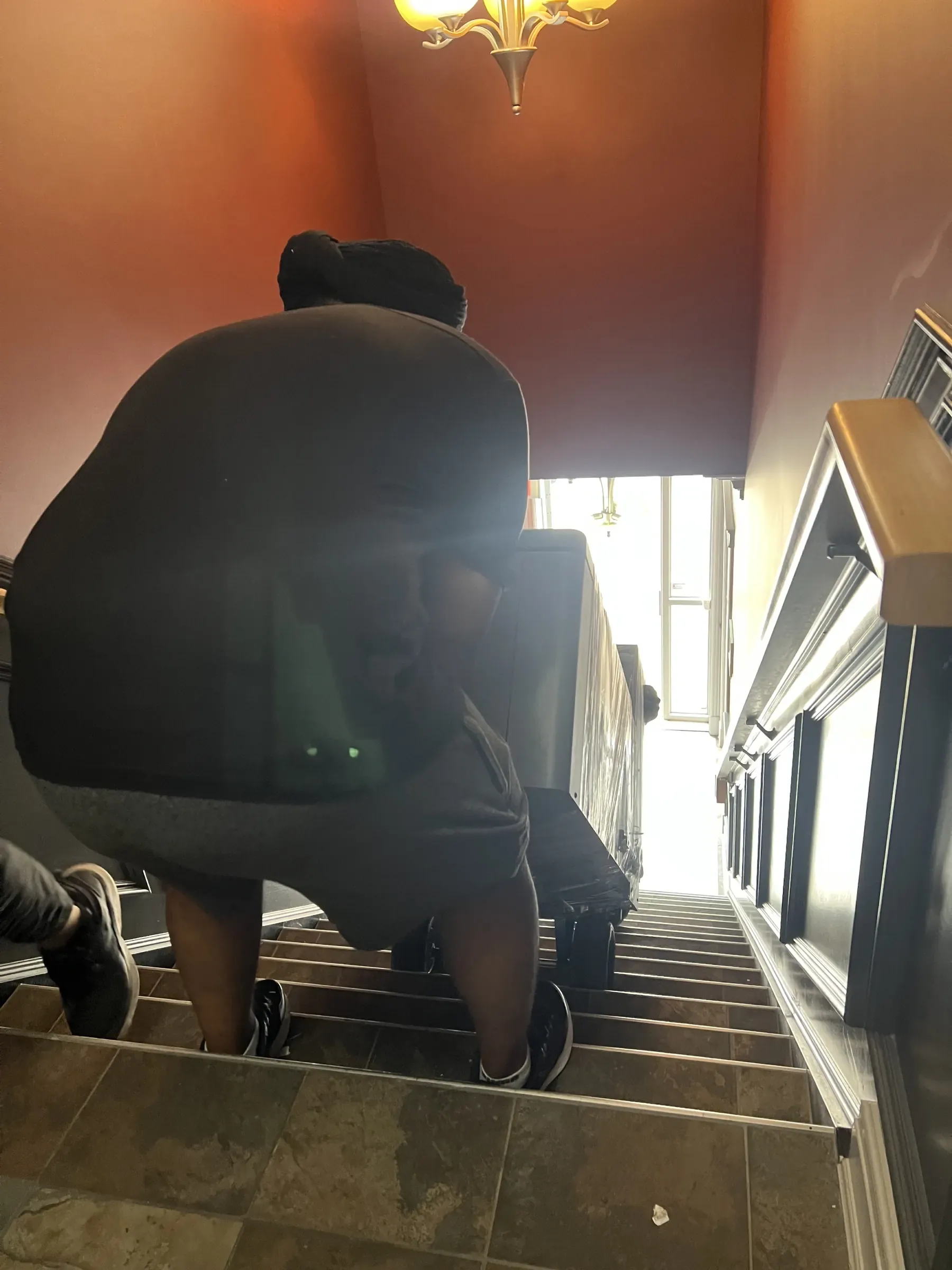 Mover carrying furniture carefully down stairs during a local move