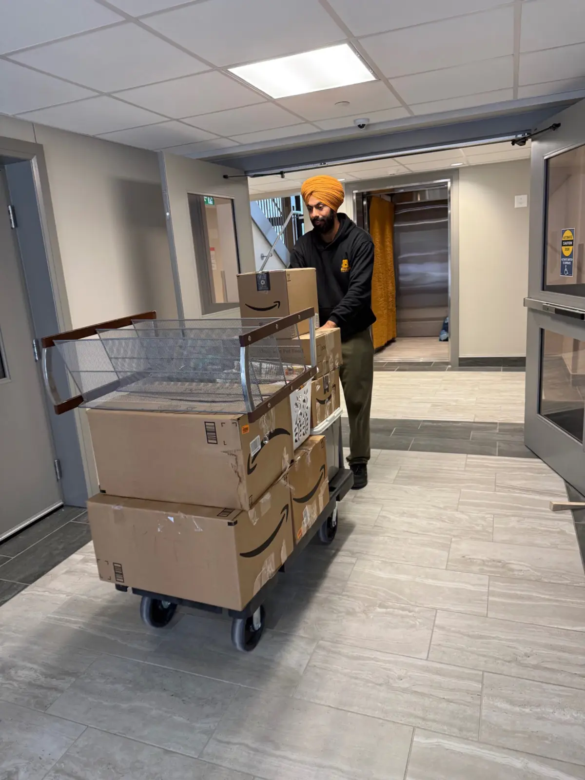 Experienced London apartment mover using a cart beside an elevator