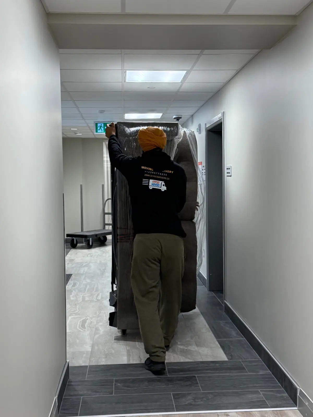 Gypsee mover transporting wrapped large furniture near an elevator