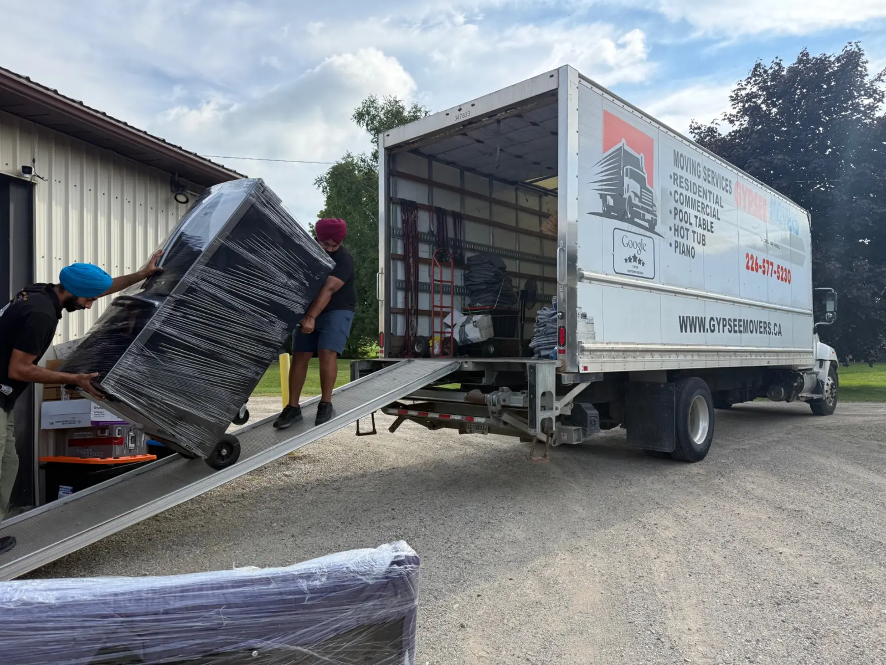 Gypsee Movers loading a wrapped vending machine into a liftgate truck