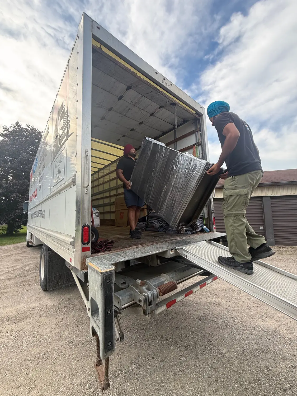 Movers guiding a wrapped vending machine into a Gypsee Movers truck