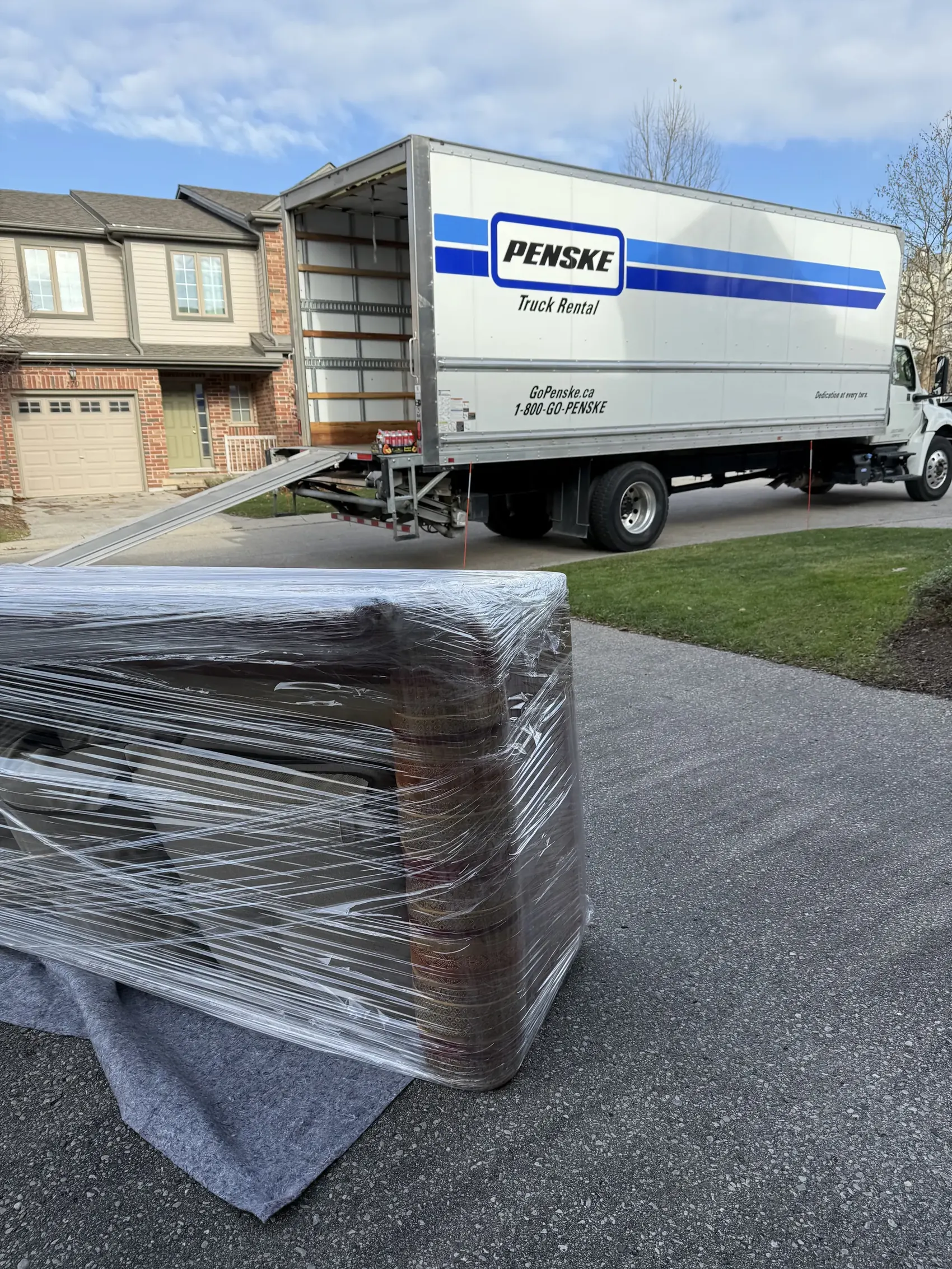 Penske truck resource used for a long-distance moving job with wrapped furniture in the foreground