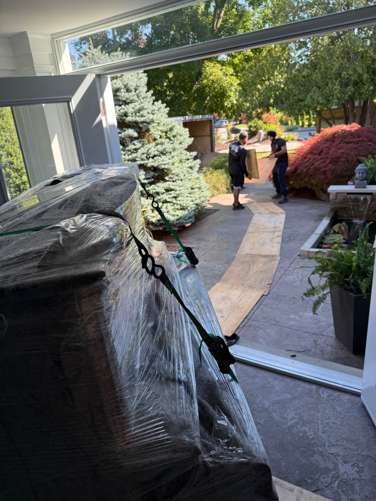 Protected piano guided through a patio doorway
