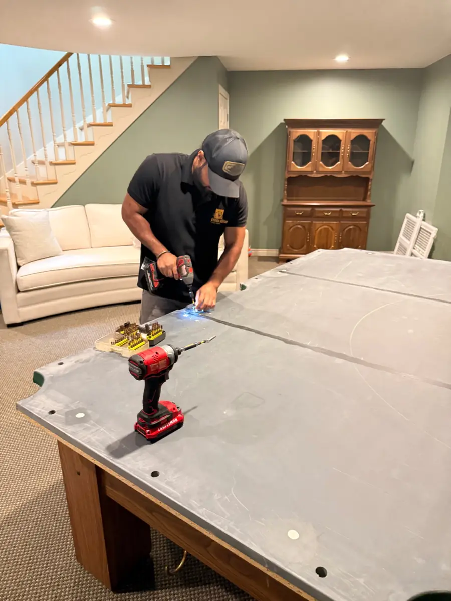 Pool table being carefully disassembled before moving