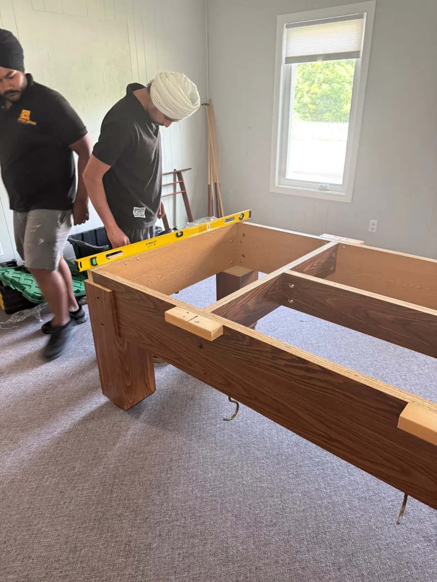 Pool table frame being assembled and levelled at its destination