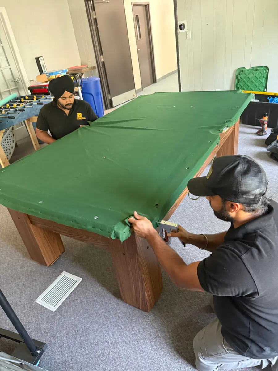 Pool table felt being stretched and professionally installed