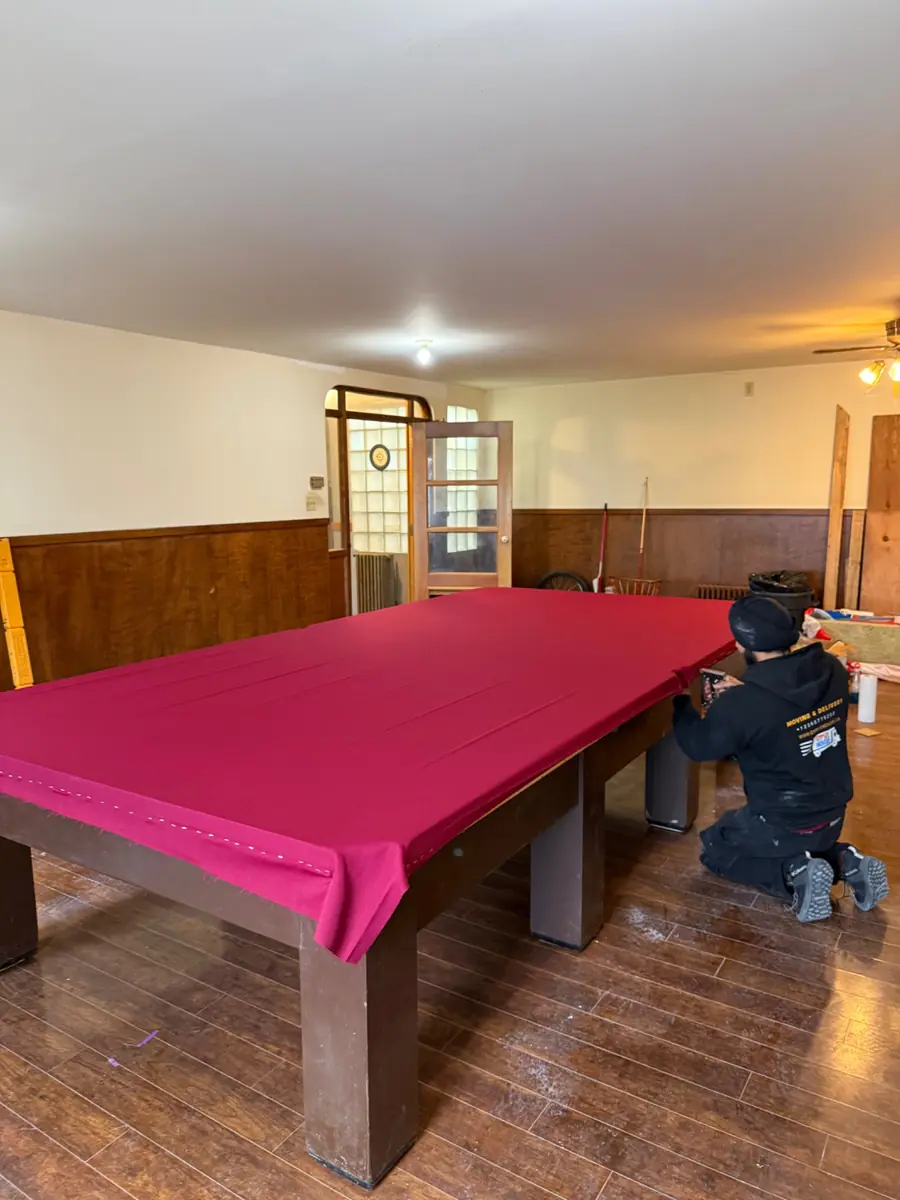 Large snooker table being professionally set up and refelted