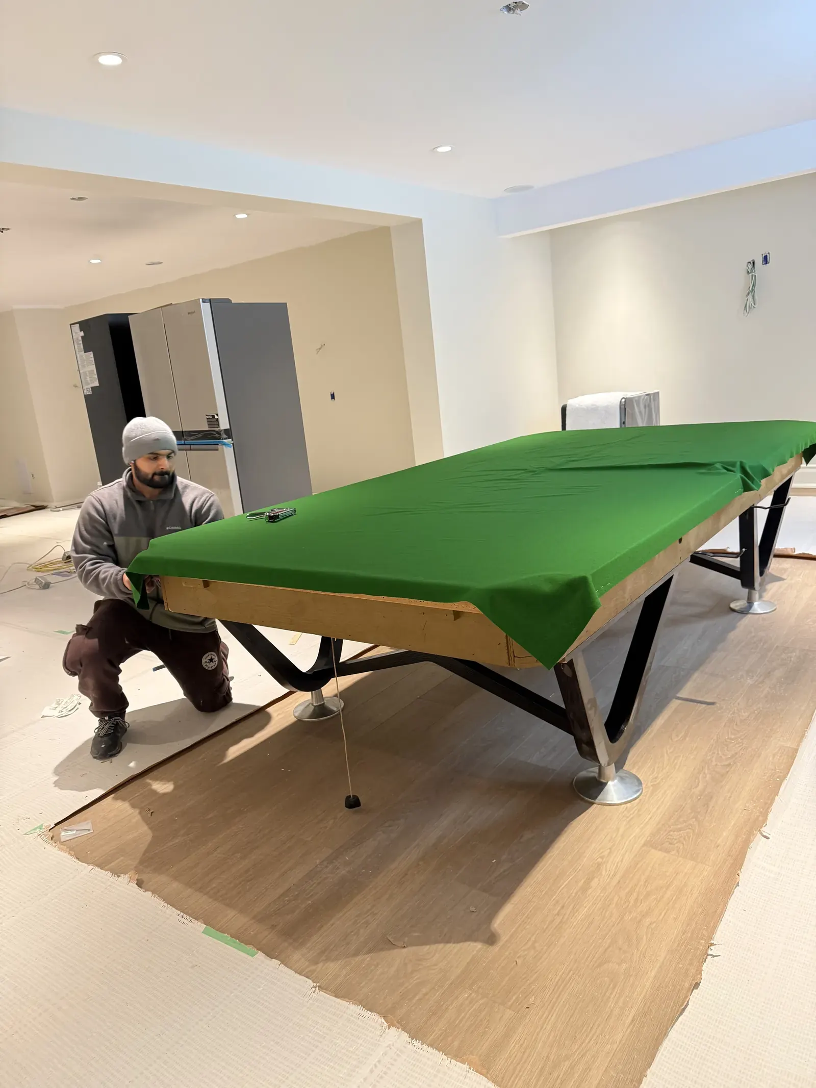 Pool table felt being trimmed and secured