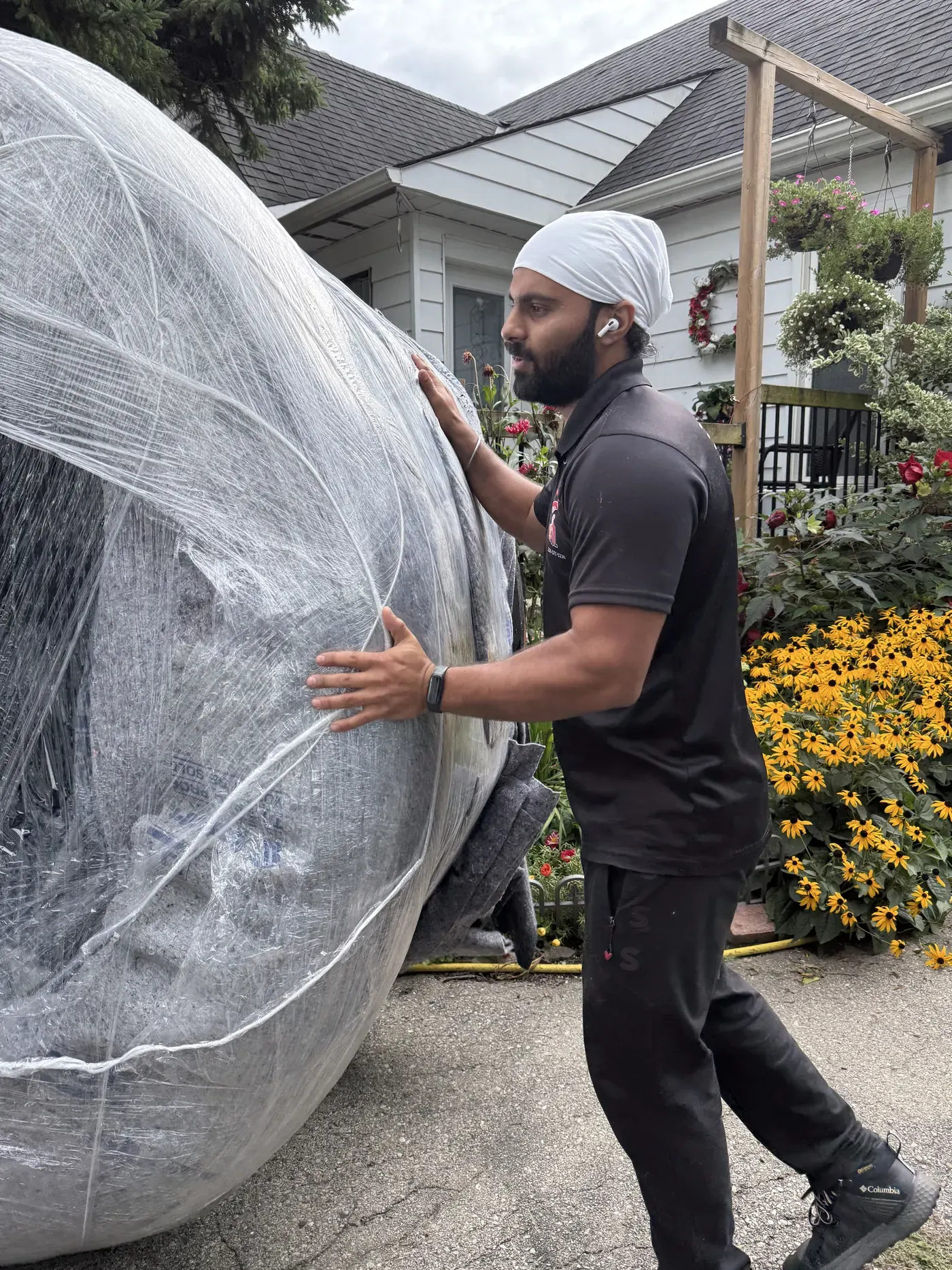 Residential movers carrying wrapped furniture through tight access during a London Ontario house move