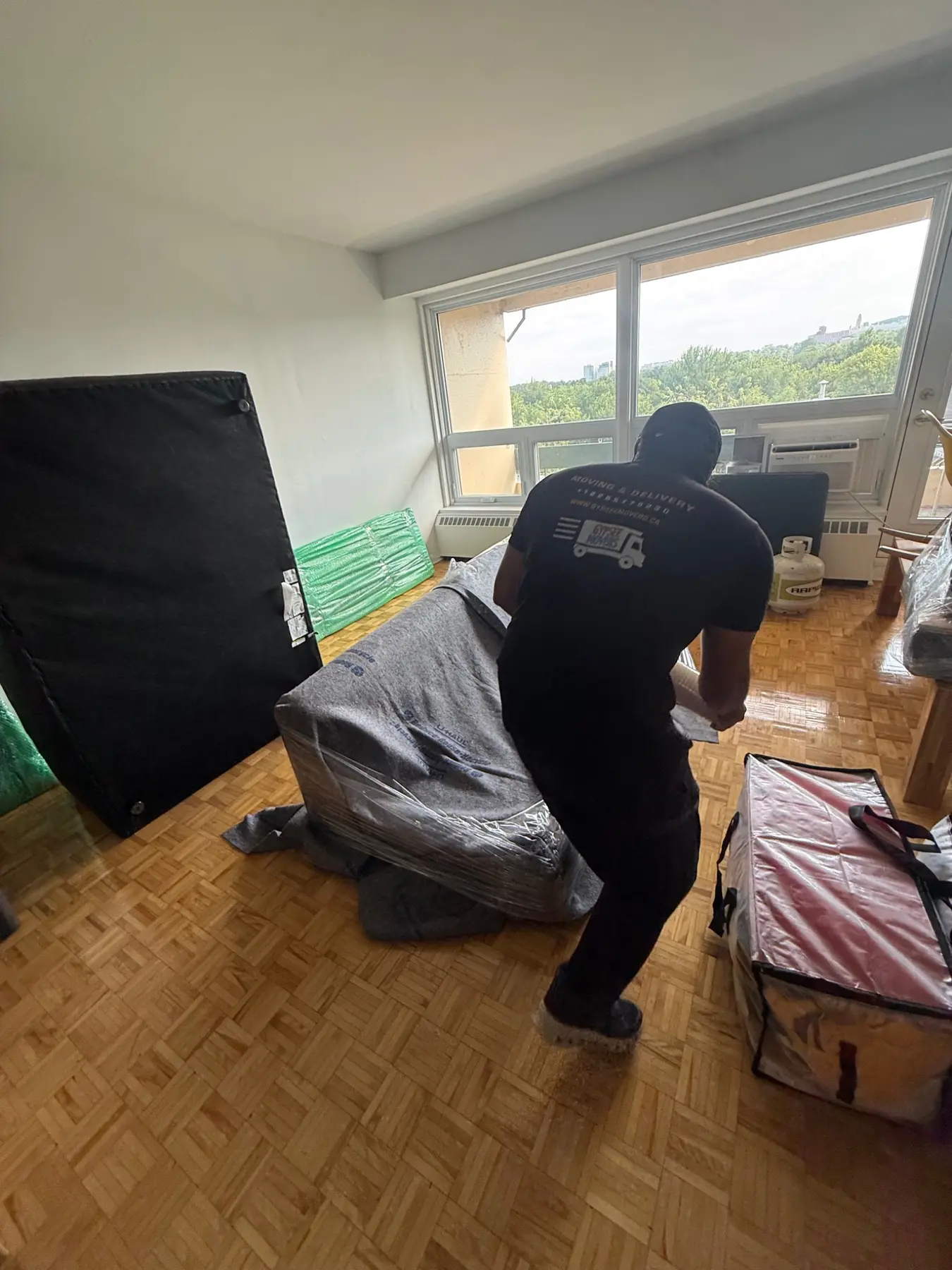 Mover wrapping a couch in blankets and plastic wrap