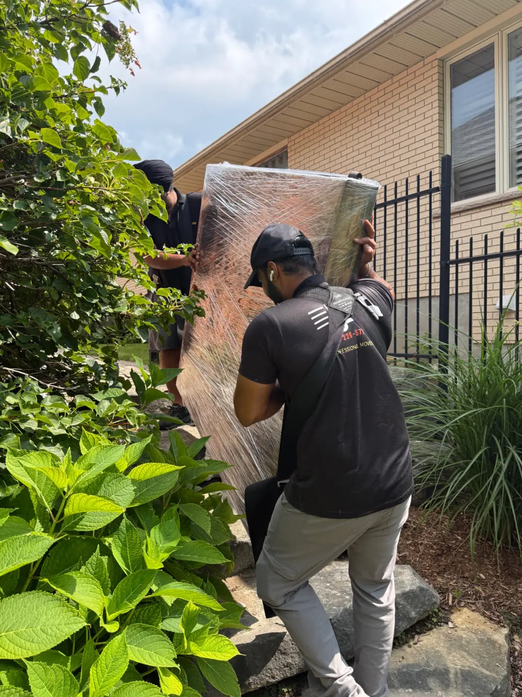 Professional movers carrying a protected piano on stairs