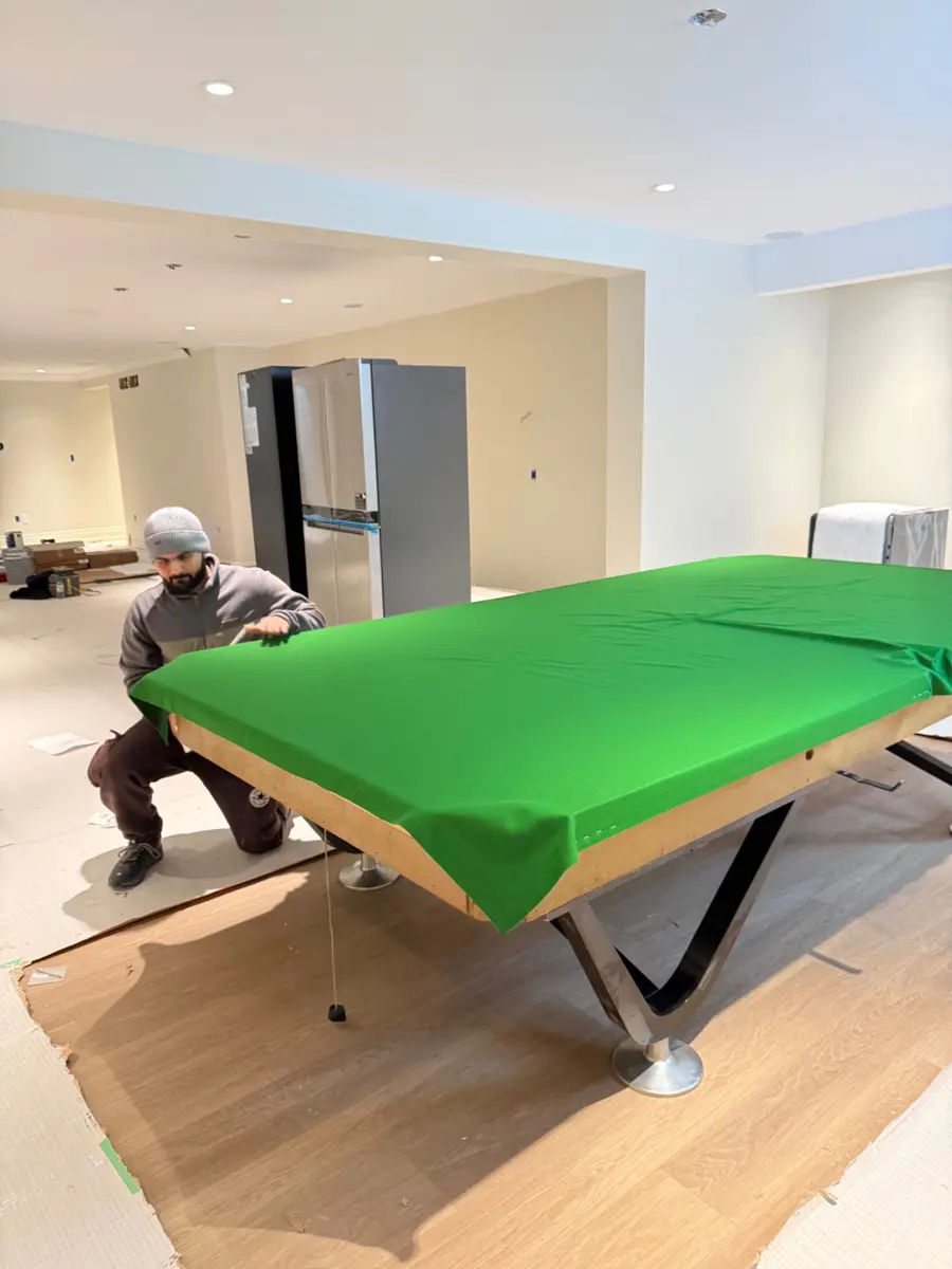 Technician stretching new green pool table cloth