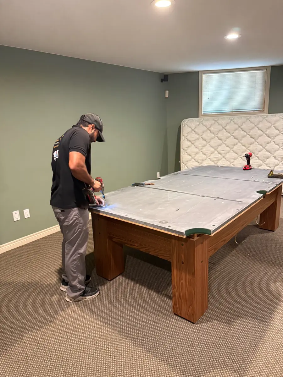 Pool table specialist removing slate hardware
