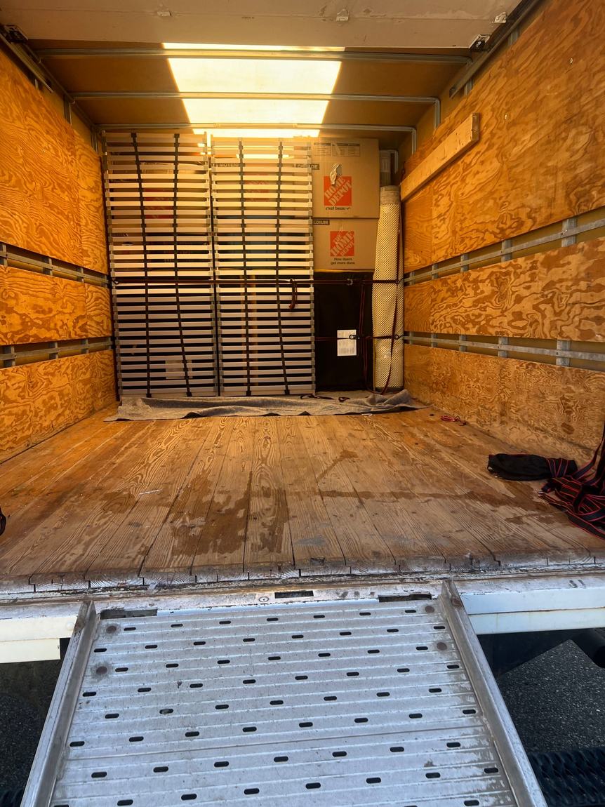 Organized truck loading with boxes, bins, mattresses, and wrapped furniture