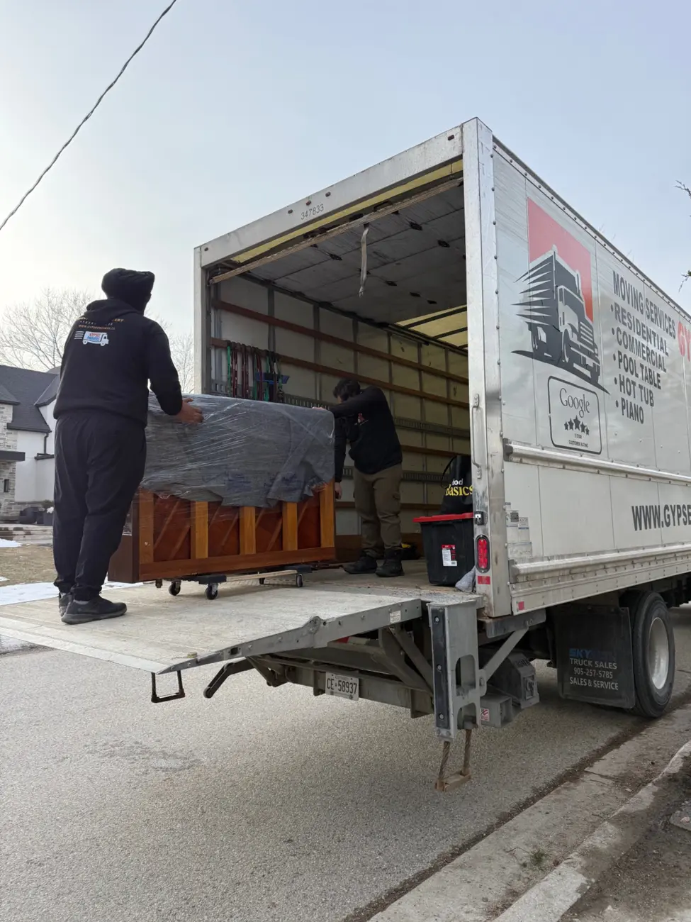 Protected piano being loaded by hydraulic liftgate